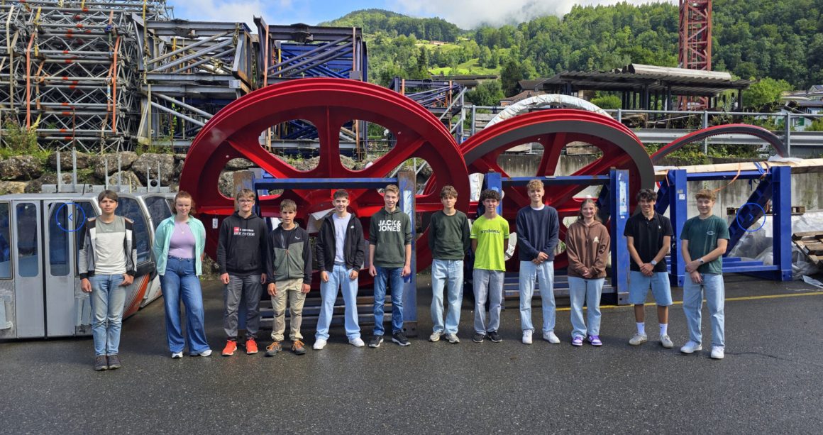 Gruppe junger Menschen vor Antriebsräder von Seilbahnen
