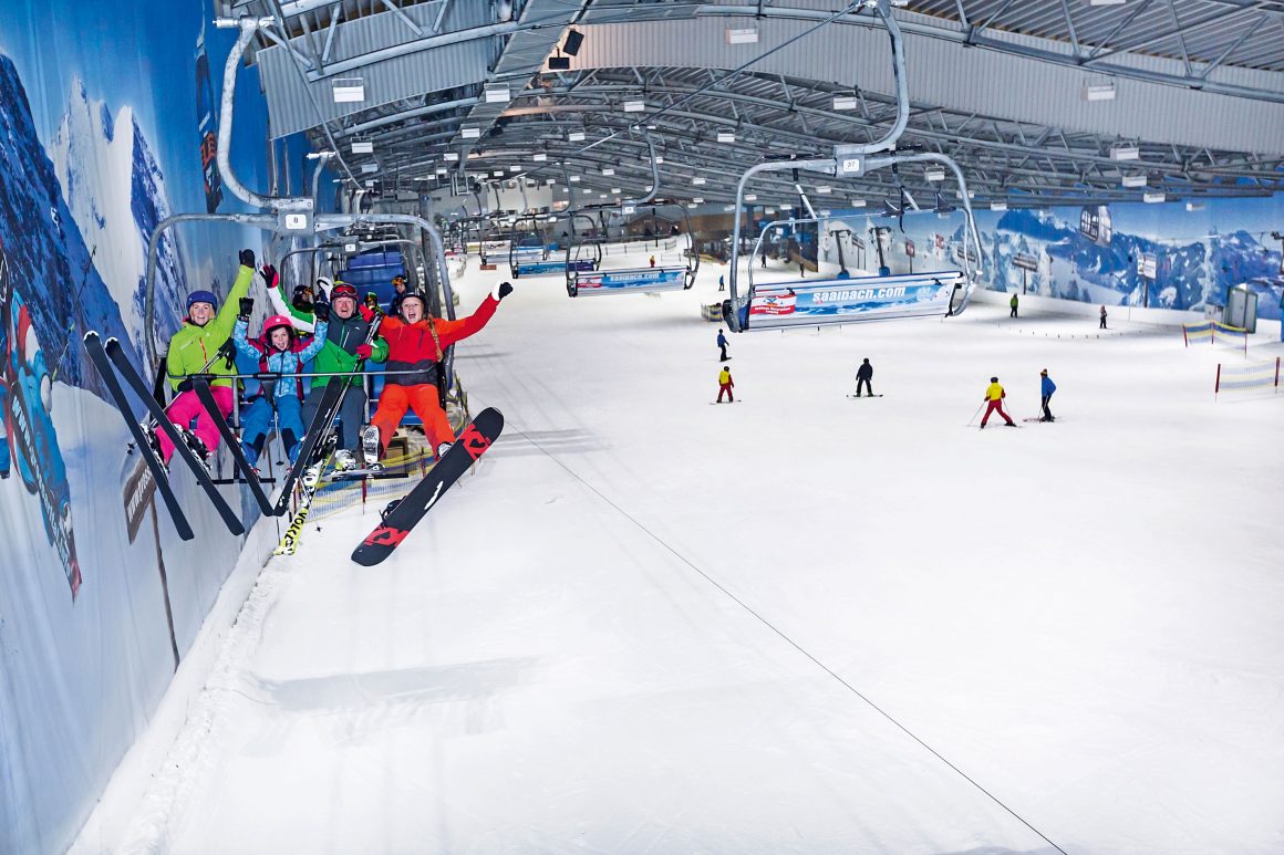 Sesselbahn mit Fahrgästen und Skifahrer in Skihalle