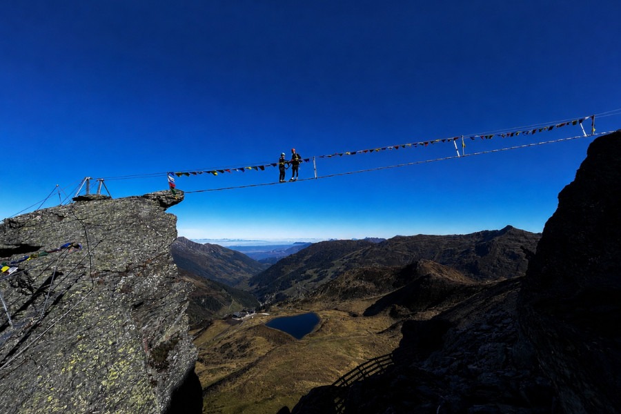 Klettersteig verbindet zwei große Felsen und zwei Kletterer überqueren ihn.