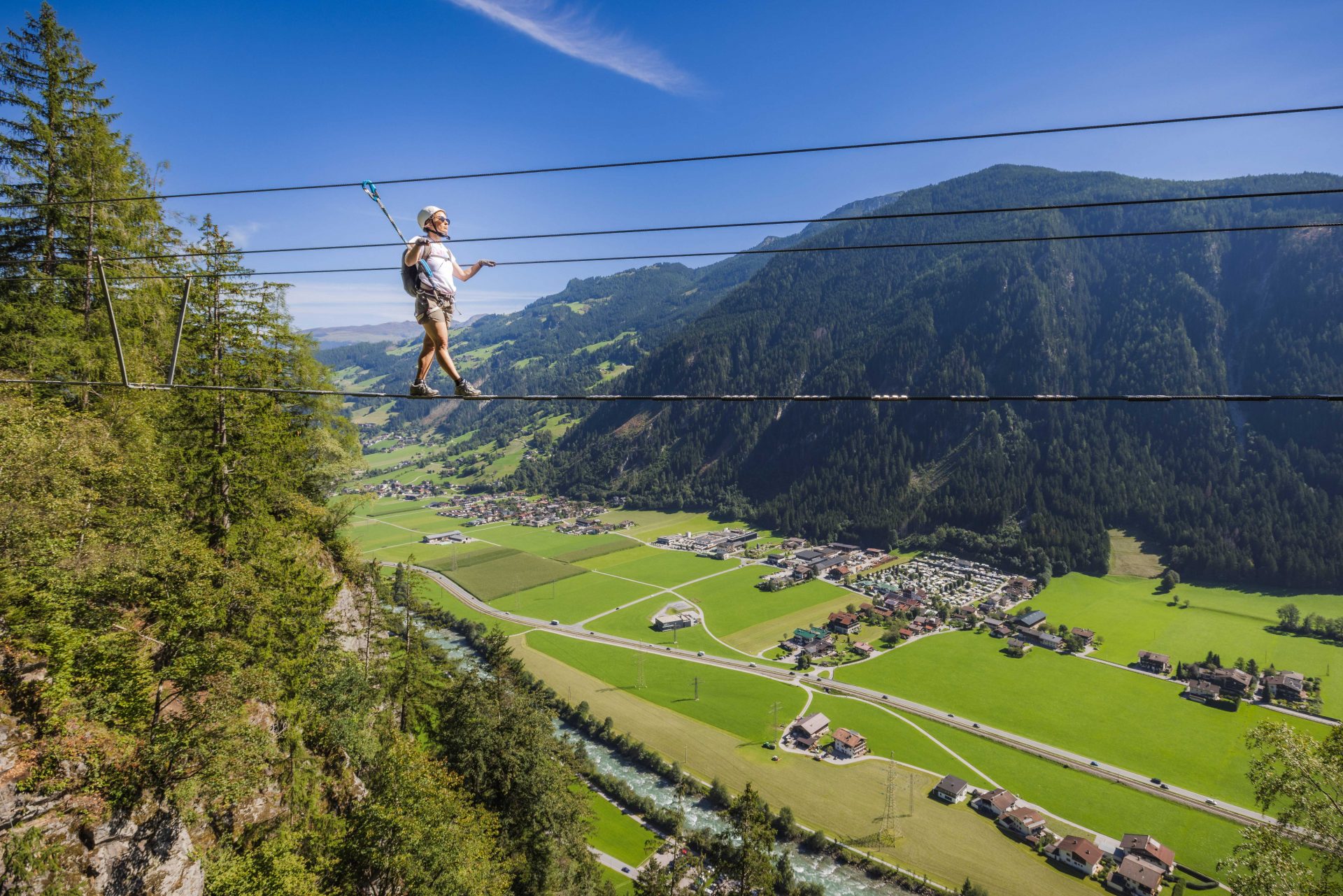 Ein Kletterer überquert einen Klettersteig und schwebt quasi über dem Tal.