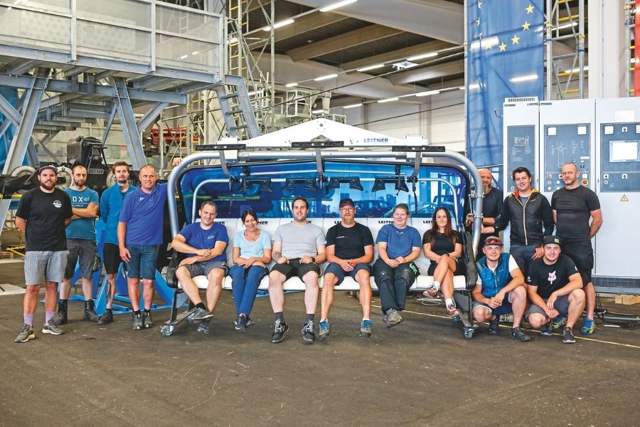 Große Schülergruppe posiert vor Seilbahnsessel für Foto